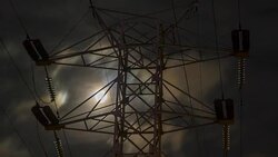 the moon in the cloudy sky, visible through the power line support, time lapse. Stock Footage
