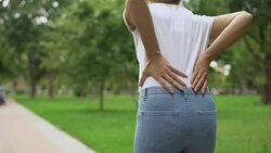 Slim woman walking in park, feeling back ache discomfort, rheumatism, healthcare Stock Footage