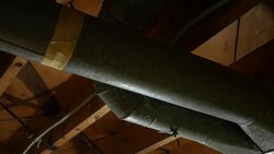 Camera pans over taped side of air duct work in basement Stock Footage