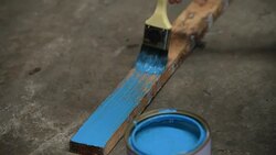 Human hand is painting blue color on wooden stick Stock Footage