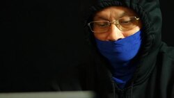 Man in hood and mask  typing laptop Stock Footage