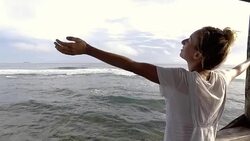 Young woman enjoying sea breeze from wooden pier over sea arms outstretched Stock Footage