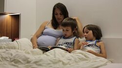 Pregnant mum, reading bedtime story for her sons Stock Footage