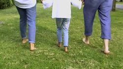 Barefoot girl walking on grass with parents Stock Footage