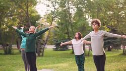 Active young people are exercising in park doing yoga exercises standing on mats on warm autumn day at weekend. Healthy lifestyle and youth concept. Stock Footage