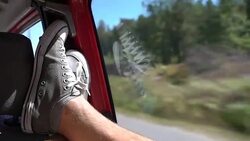 A young man enjoys traveling by car throws her legs on the window. Stock Footage