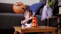 Asian baby girl with pumpkin toy while eating and singing song with mother at home Stock Footage
