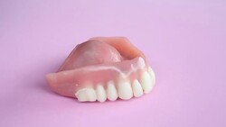 Dentures on a rotating pink plate Stock Footage
