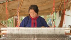 Traditional textile manufacture in craft village where old women work on wooden weaving loom machines and spin yarn creating silk or cotton fabric. Silk weaving in Thailand. Stock Footage