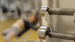 Blurred image of the girl in gym, she pumps the muscles of hands lying on bench. Stock Footage