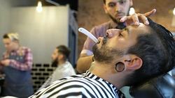 Young barber shaving man with straight razor Stock Footage