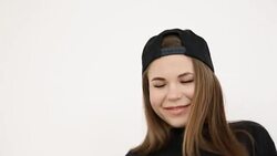 a teenage girl in black hip-hop clothes and a cap dances at the white wall- close-up, handheld shoot, small depth of field Stock Footage