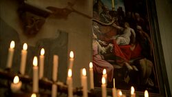 MEDIUM ANGLE OF RELIGIOUS PAINTING OR MURAL HANGING ON STONE WALL. SCONCE AND CANDLES IN FG. COULD BE IN CHURCH. Stock Footage