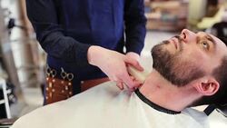 barber treating male neck with alum bar at shop Stock Footage