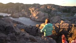 Two little girls play on a rocky northern seashore. Stock Footage