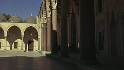 WIDE ANGLE OF INTERIOR STONE COURTYARD. PILLARS OR COLUMNS. STRIPED POINTED ARCHES. ISLAMIC ARCHITECTURE. SULEYMANIYE MOSQUE. DOMES VISIBLE IN BG. Stock Footage