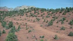 AERIAL OF ARIZONA DESERT WITH RED ROCKS AND MOUNTAINS. ONE MAN WAVING HANDS FOR HELP FROM CLIFF. MULTIPLE TAKES. Stock Footage