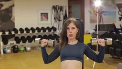 Girl trains in the gym with dumbbells, she trains the muscles of back and hands. Stock Footage