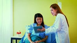 Young Asian female doctor and woman patient lying in bed while discussing and consultation medical examination at hospital room , Healthcare and medical concept, Doctor and patient Stock Footage