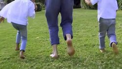 Barefoot father holding hands with kids and walking on grass Stock Footage