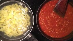 A chef in a professional kitchen cooking homemade tomato sauce and mashed potatoes in metal pan on rustic table background in the kitchen. Concept diet, food, Italian and nutrition. Stock Footage