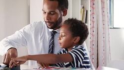 Businessman father sitting at desk in sons bedroom helping him with homework Stock Footage